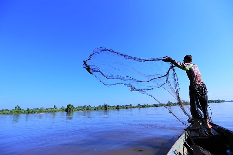 Fisherman casting a net over blue waters