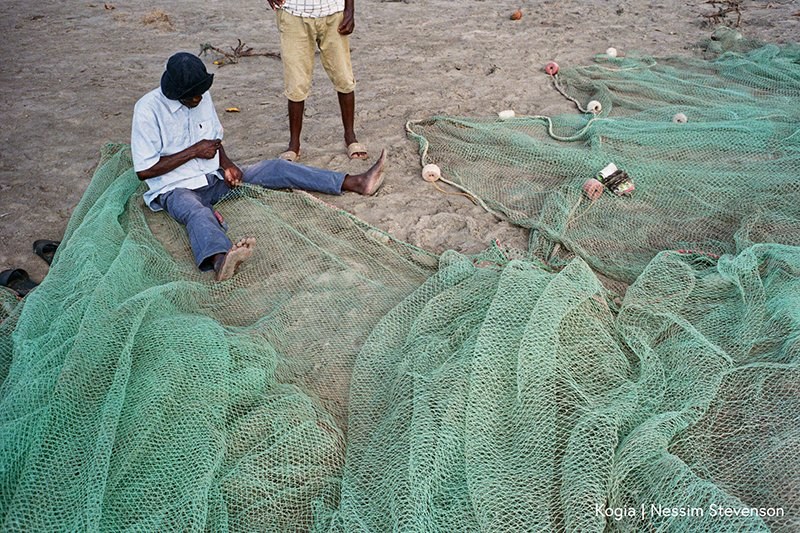 Fisherman mending green nets